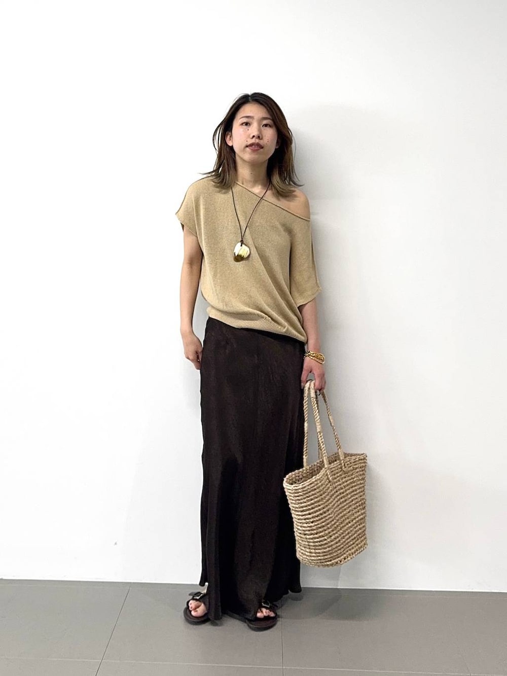 ベージュ系のかごバッグ、ベージュ系のニット/セーター、ブラウン系のスカートを着用したレディースの春コーディネートの2枚目の写真