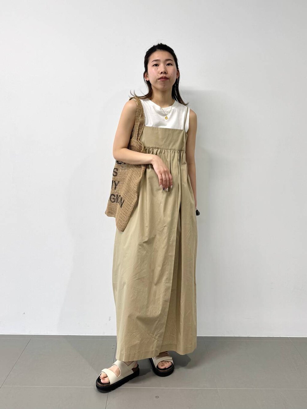 ベージュ系のトートバッグ、ホワイト系のタンクトップ、ベージュ系のワンピースを着用したレディースの夏コーディネートの2枚目の写真