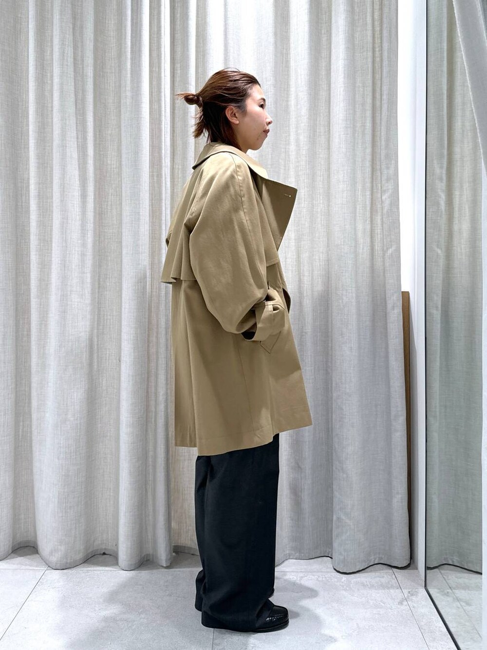 グレー系のスラックス、イエロー系のトレンチコート、イエロー系のニット/セーターを着用したレディースの秋コーディネートの5枚目の写真