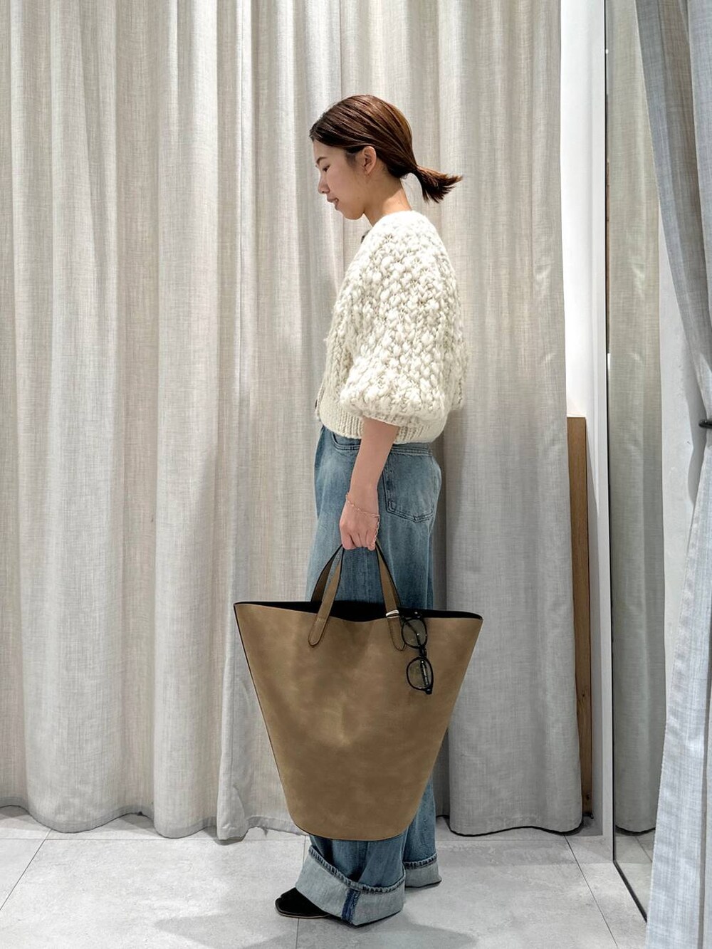 ベージュ系のカーディガン/ボレロ、ブラウン系のサンダル、ブルー系のデニムパンツを着用したレディースの秋コーディネートの3枚目の写真