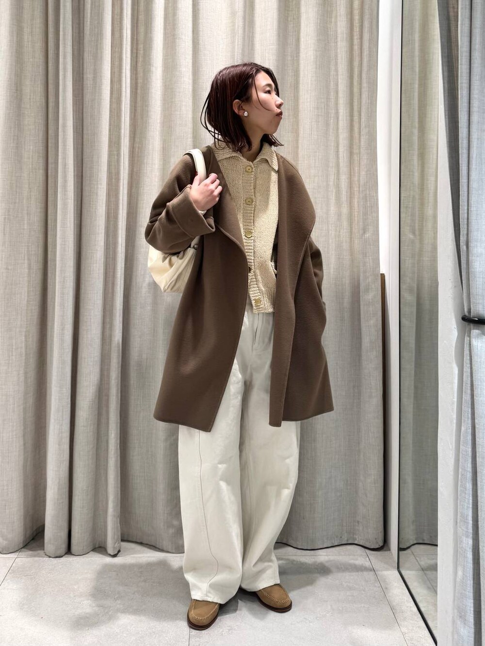 ベージュ系のショルダーバッグ、グリーン系のピーコート、ホワイト系のその他パンツを着用したレディースの冬コーディネートの2枚目の写真