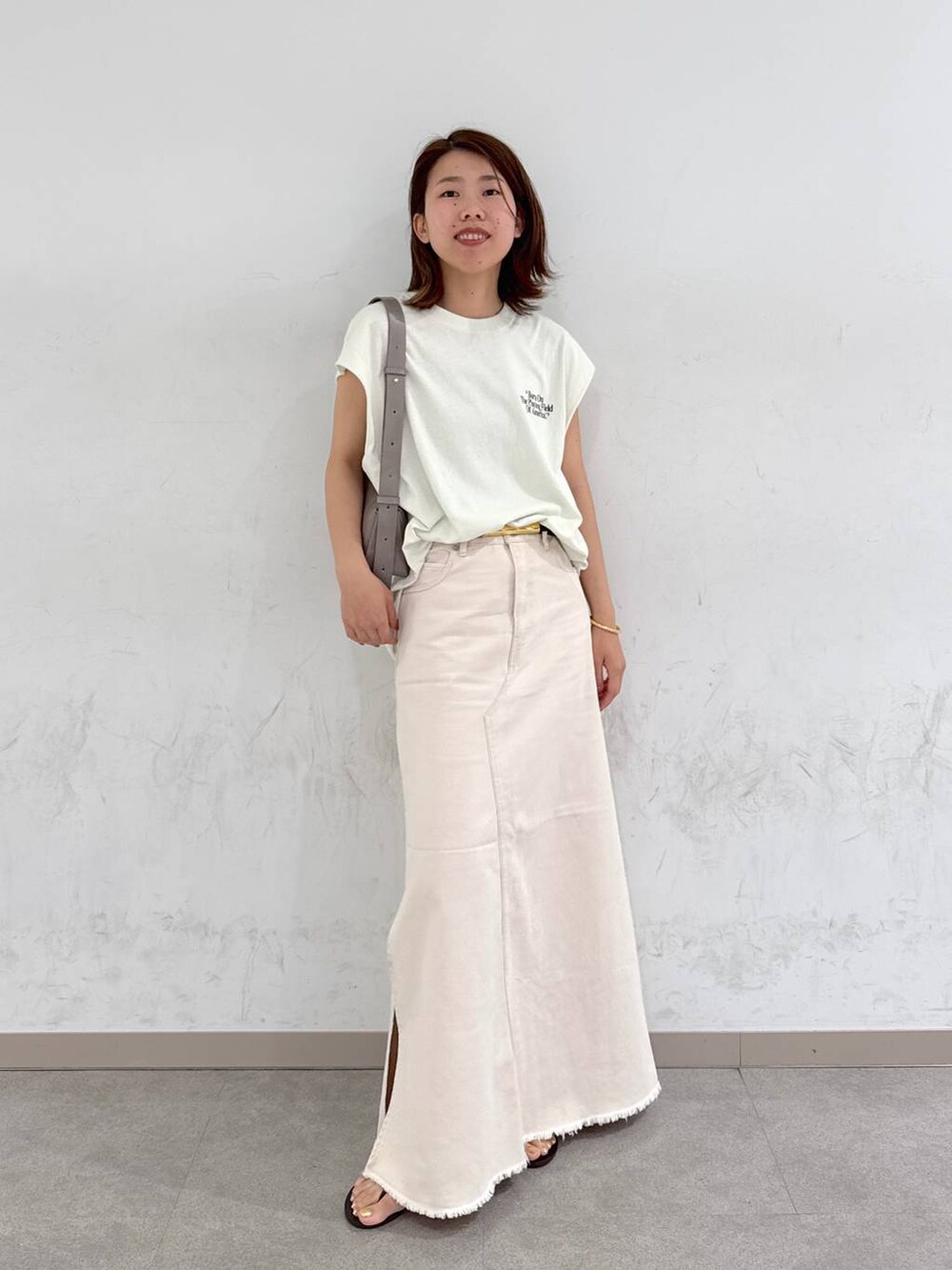 ブラウン系のサンダル、ホワイト系のTシャツ/カットソー、グリーン系のショルダーバッグを着用したレディースの夏コーディネートの2枚目の写真