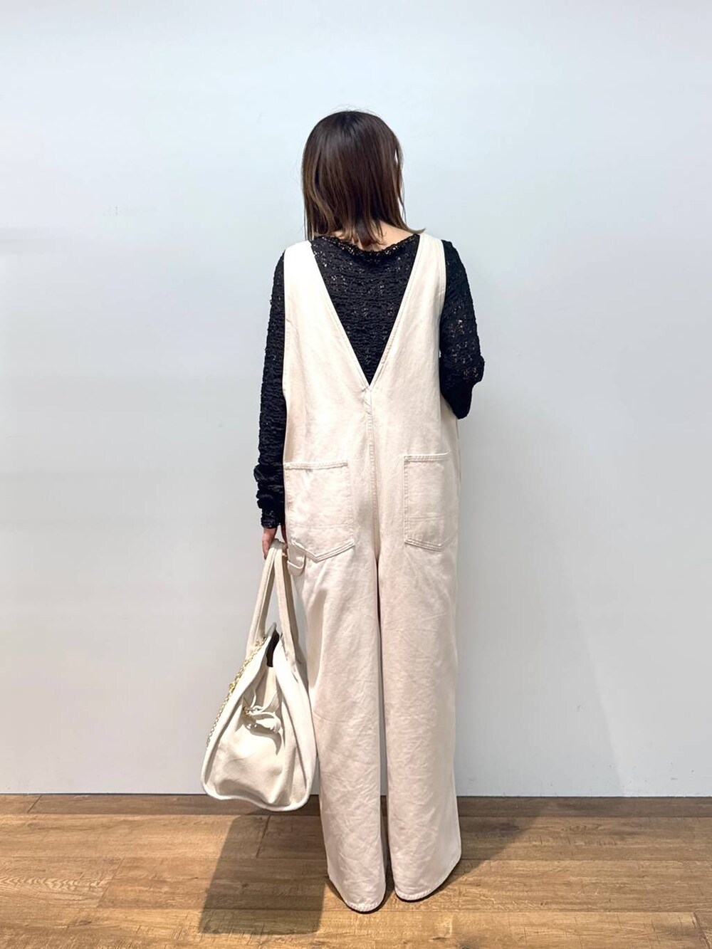 ホワイト系のサロペット/オーバーオール、ブラック系のTシャツ/カットソー、ブラック系のサンダルを着用したレディースの夏コーディネートの5枚目の写真