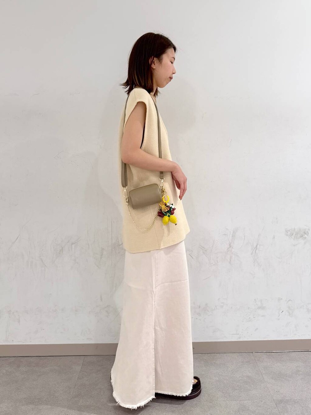 オレンジ系のキャミソール、ホワイト系のスカート、ベージュ系のベストを着用したレディースの夏コーディネートの5枚目の写真