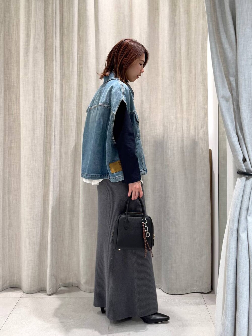 ブルー系のTシャツ/カットソー、グレー系のスカート、ブラック系のブーツを着用したレディースの冬コーディネートの8枚目の写真