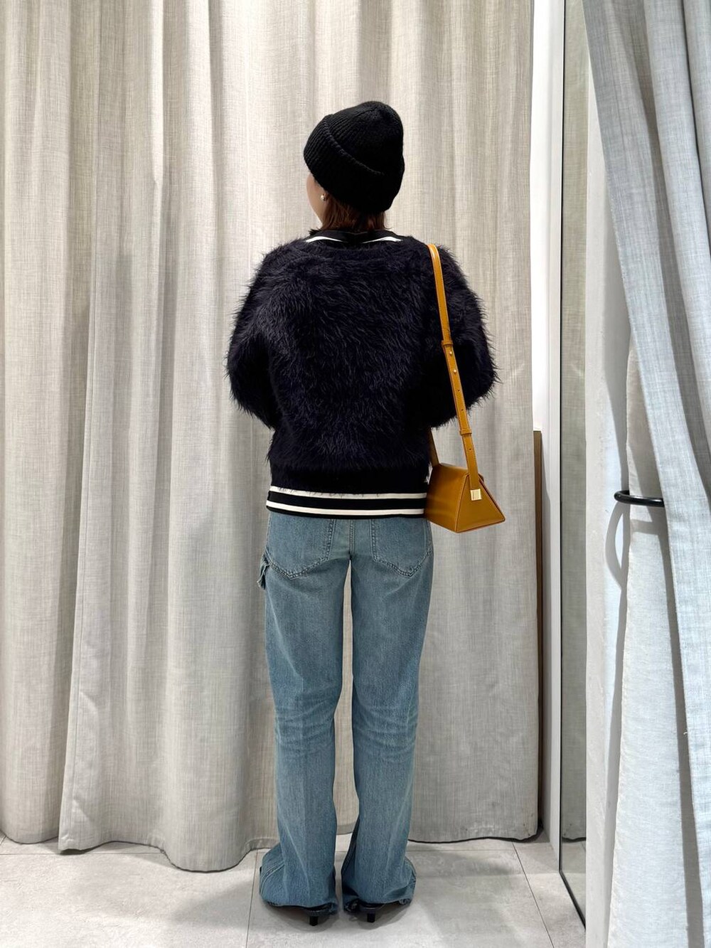 ブラック系のTシャツ/カットソー、ブルー系のカーディガン/ボレロ、ブルー系のデニムパンツを着用したレディースの冬コーディネートの6枚目の写真