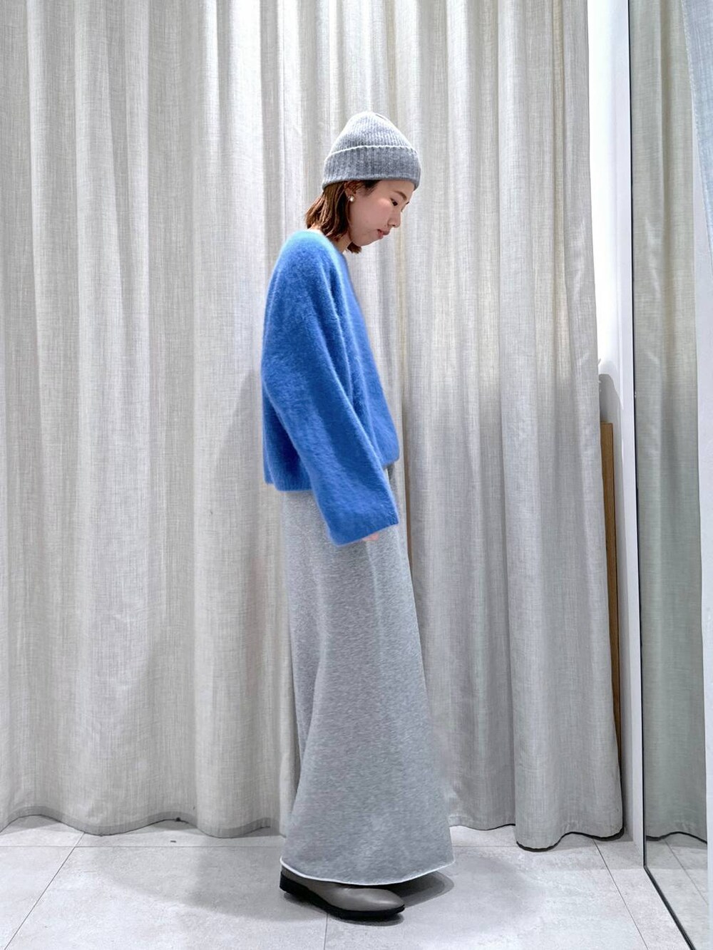 ブルー系のニット/セーター、シルバー系のショルダーバッグ、グレー系のスカートを着用したレディースの秋コーディネートの6枚目の写真