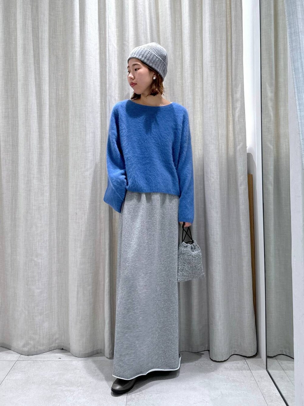 ブルー系のニット/セーター、シルバー系のショルダーバッグ、グレー系のスカートを着用したレディースの秋コーディネートの3枚目の写真