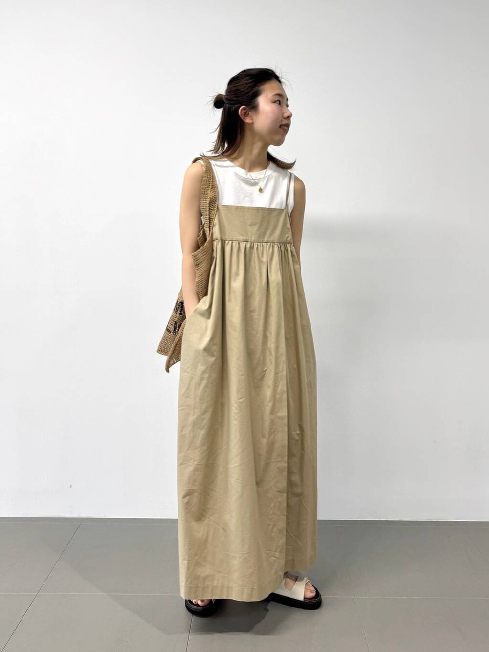 ベージュ系のトートバッグ、ホワイト系のタンクトップ、ベージュ系のワンピースを着用したレディースの夏コーディネートの3枚目の写真