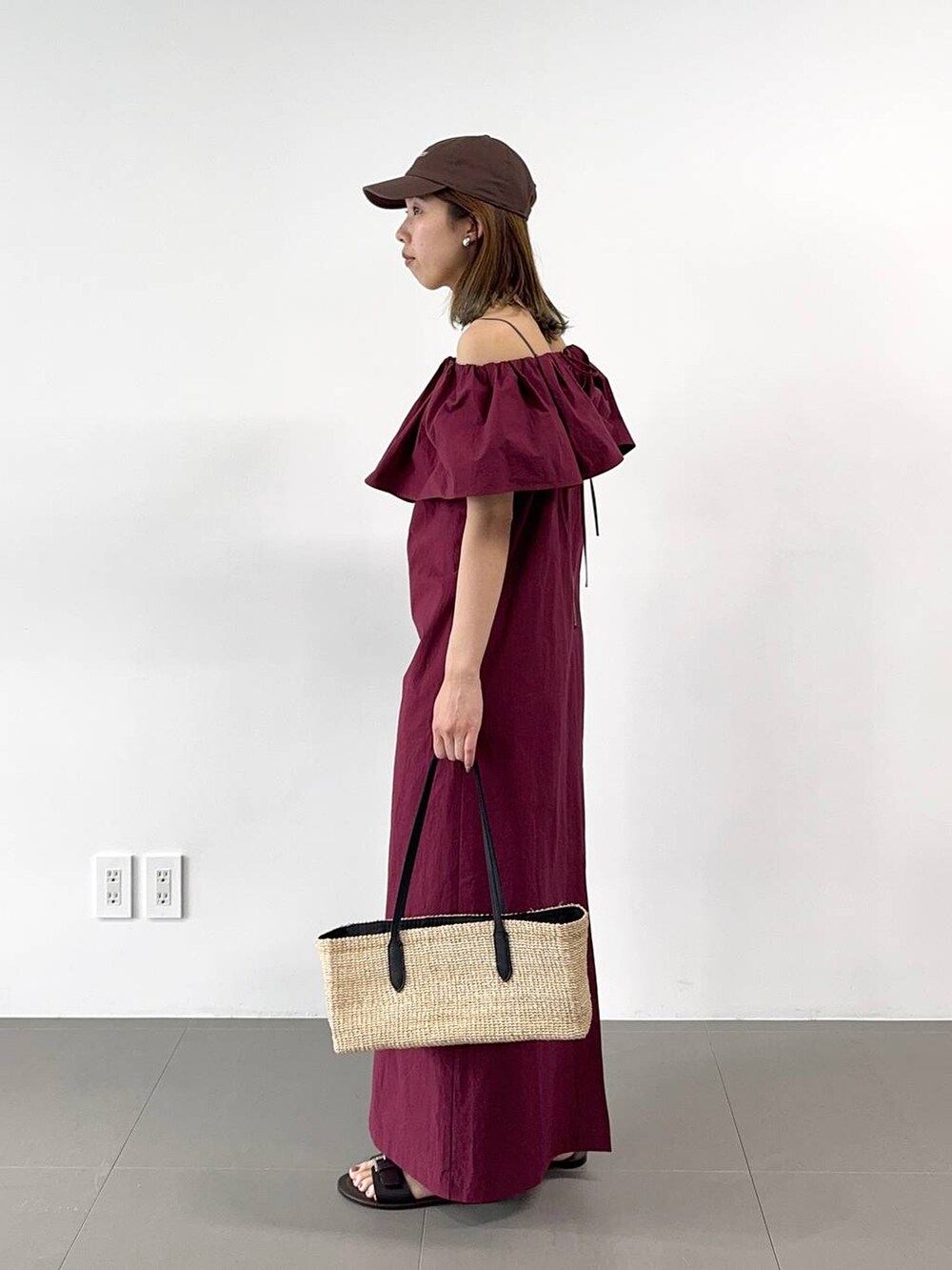 ベージュ系のかごバッグ、レッド系のワンピース、ブラウン系のキャップを着用したレディースの春コーディネートの3枚目の写真