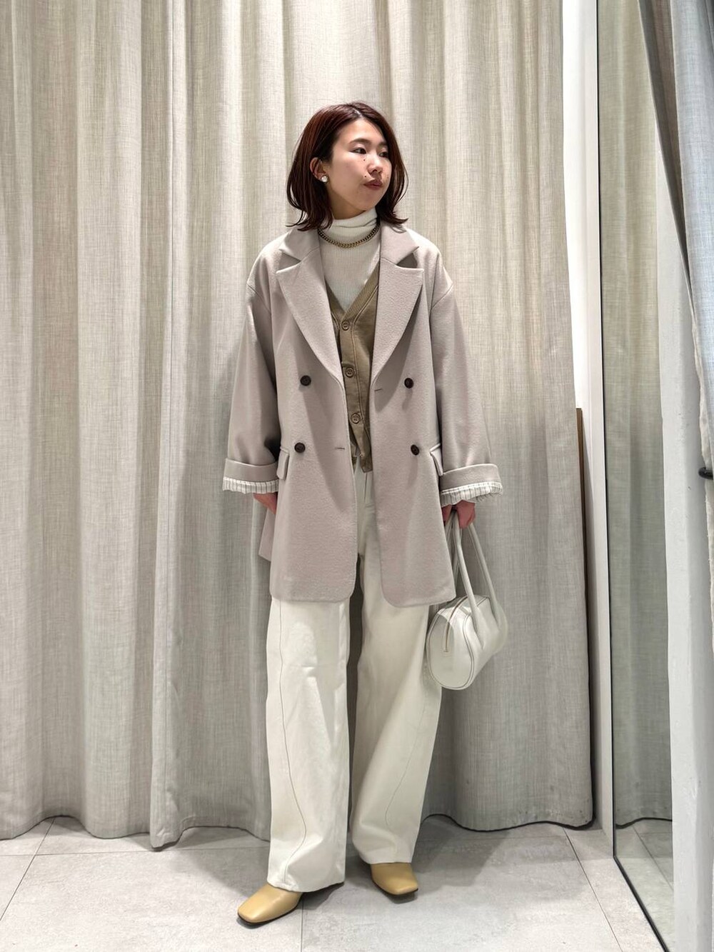 ホワイト系のニット/セーター、ベージュ系のテーラードジャケット、ベージュ系のカーディガン/ボレロを着用したレディースの冬コーディネートの3枚目の写真