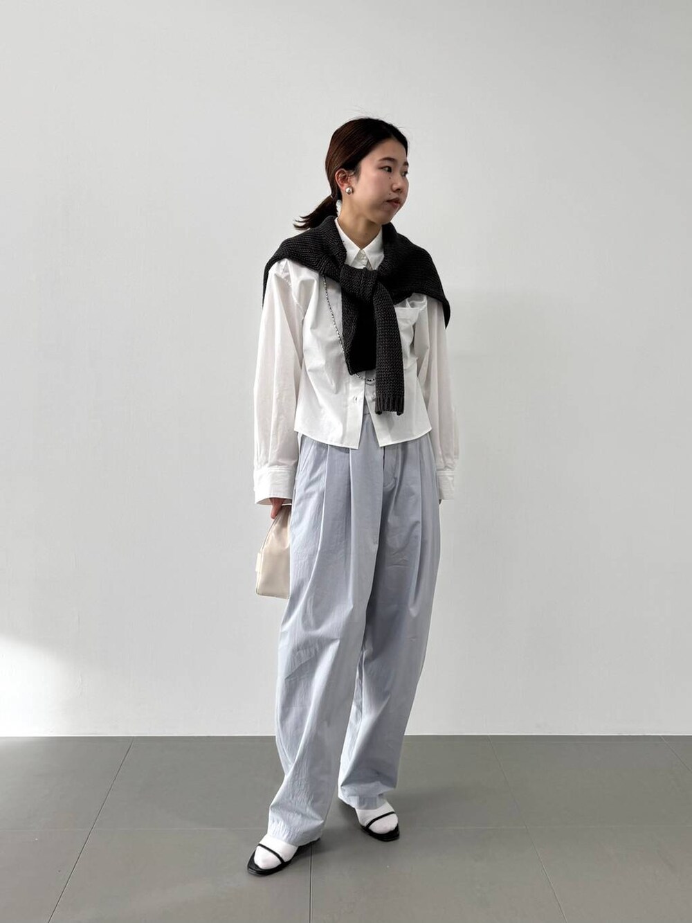 ホワイト系のハンドバッグ、ホワイト系のシャツ/ブラウス、ブラック系のサンダルを着用したレディースの冬コーディネートの4枚目の写真