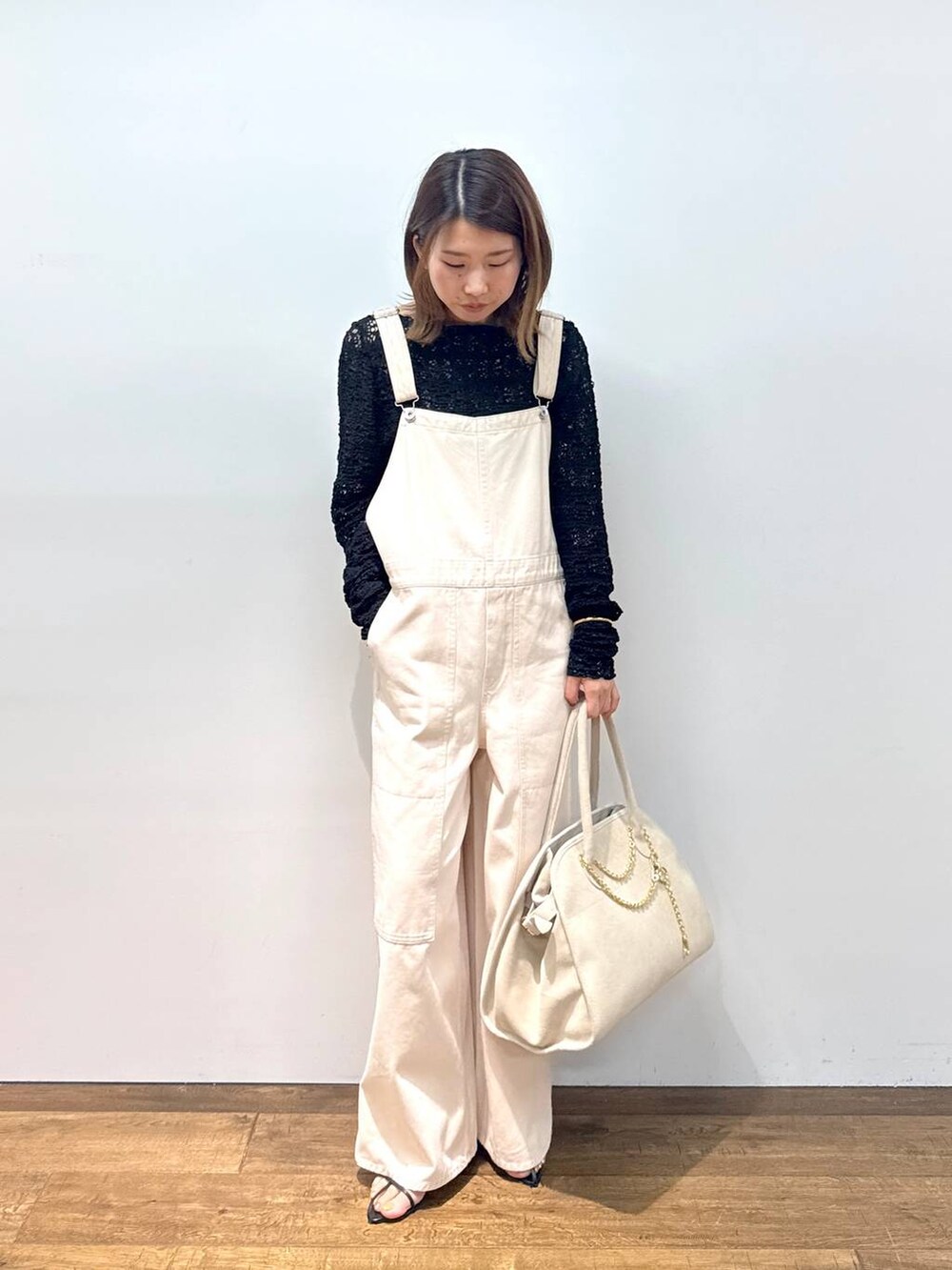 ホワイト系のサロペット/オーバーオール、ブラック系のTシャツ/カットソー、ブラック系のサンダルを着用したレディースの夏コーディネートの2枚目の写真