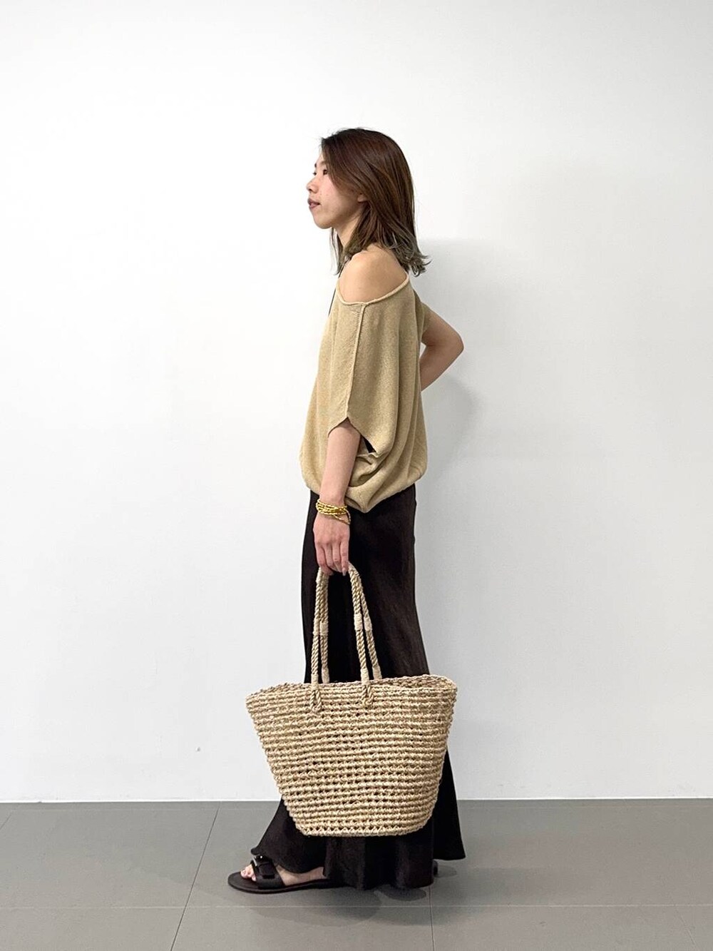 ベージュ系のかごバッグ、ベージュ系のニット/セーター、ブラウン系のスカートを着用したレディースの春コーディネートの4枚目の写真