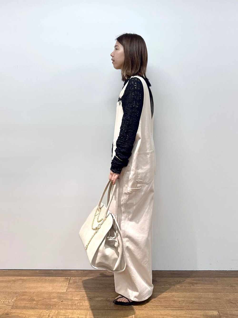 ホワイト系のサロペット/オーバーオール、ブラック系のTシャツ/カットソー、ブラック系のサンダルを着用したレディースの夏コーディネートの6枚目の写真