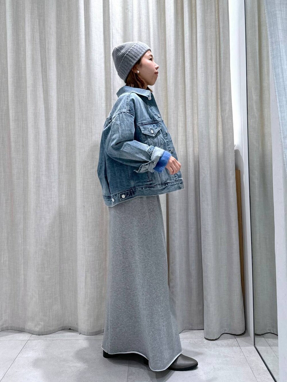 ブルー系のデニムジャケット、ブルー系のニット/セーター、シルバー系のショルダーバッグを着用したレディースの秋コーディネートの4枚目の写真