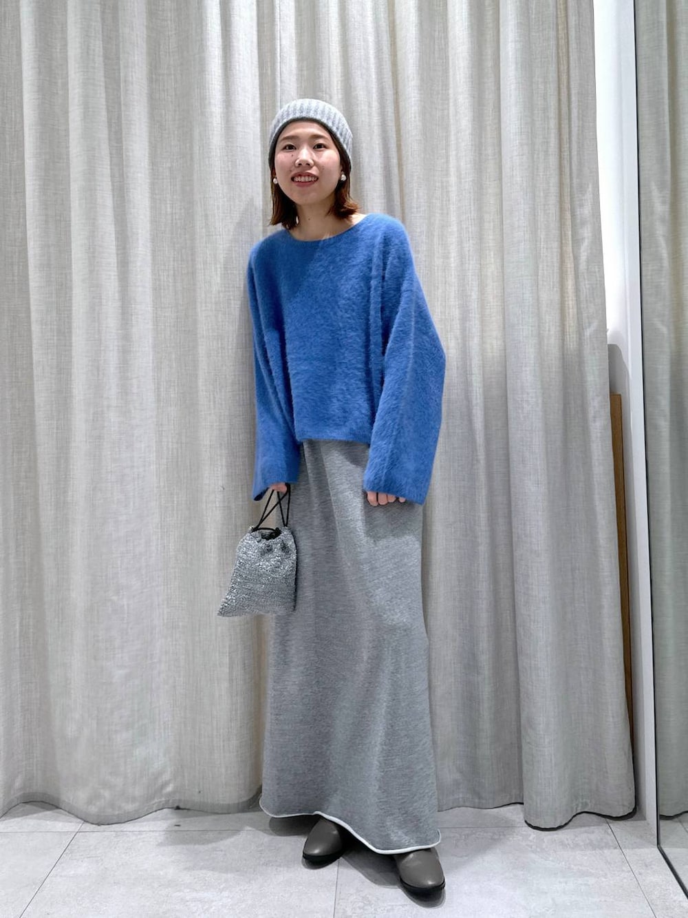 ブルー系のニット/セーター、シルバー系のショルダーバッグ、グレー系のスカートを着用したレディースの秋コーディネートの5枚目の写真