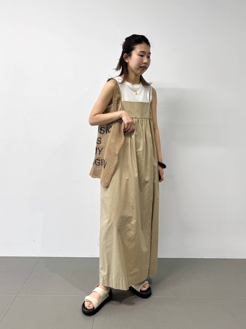 ベージュ系のトートバッグ、ホワイト系のタンクトップ、ベージュ系のワンピースを着用したレディースの夏コーディネートの5枚目の写真
