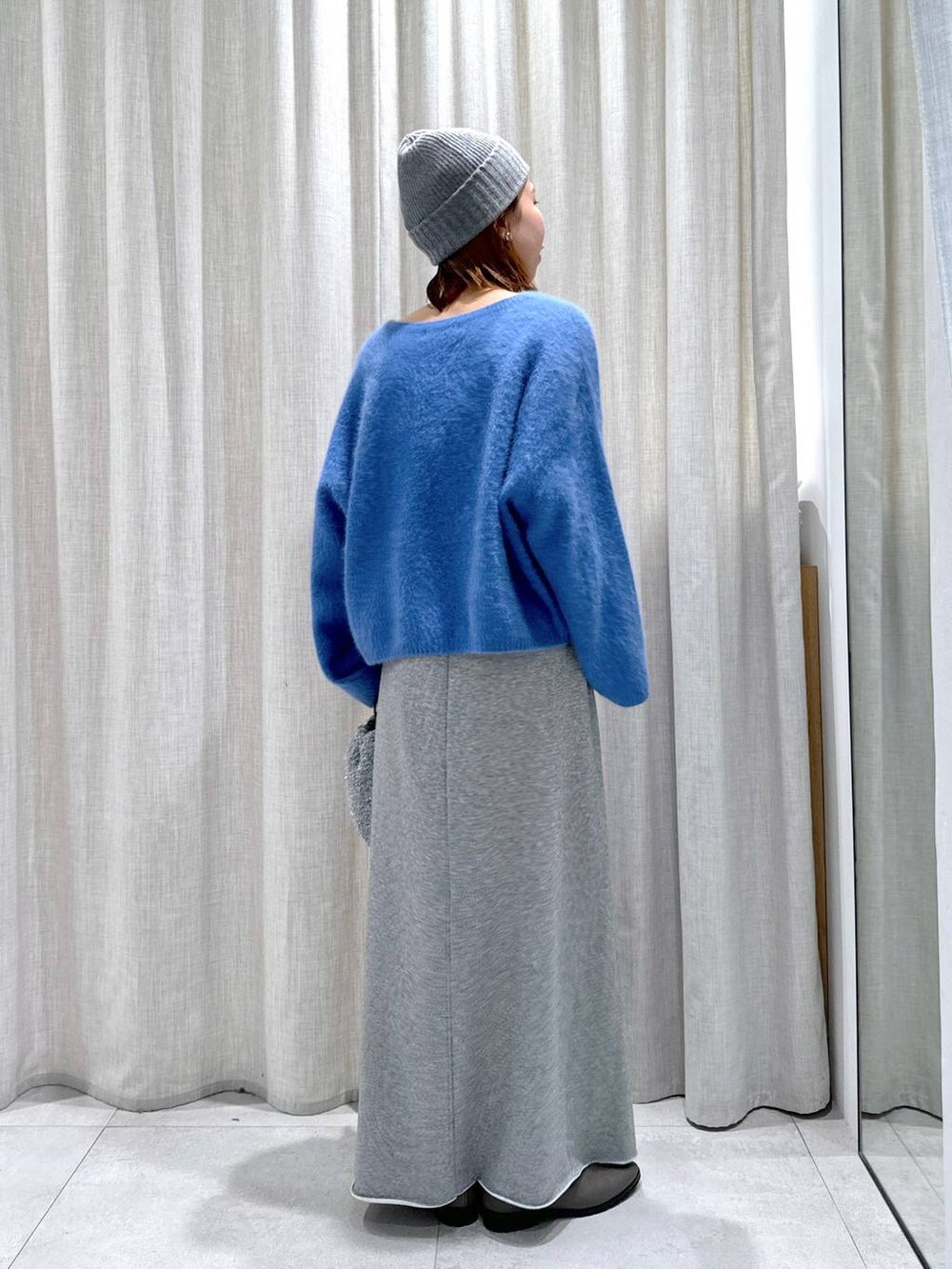 ブルー系のニット/セーター、シルバー系のショルダーバッグ、グレー系のスカートを着用したレディースの秋コーディネートの7枚目の写真