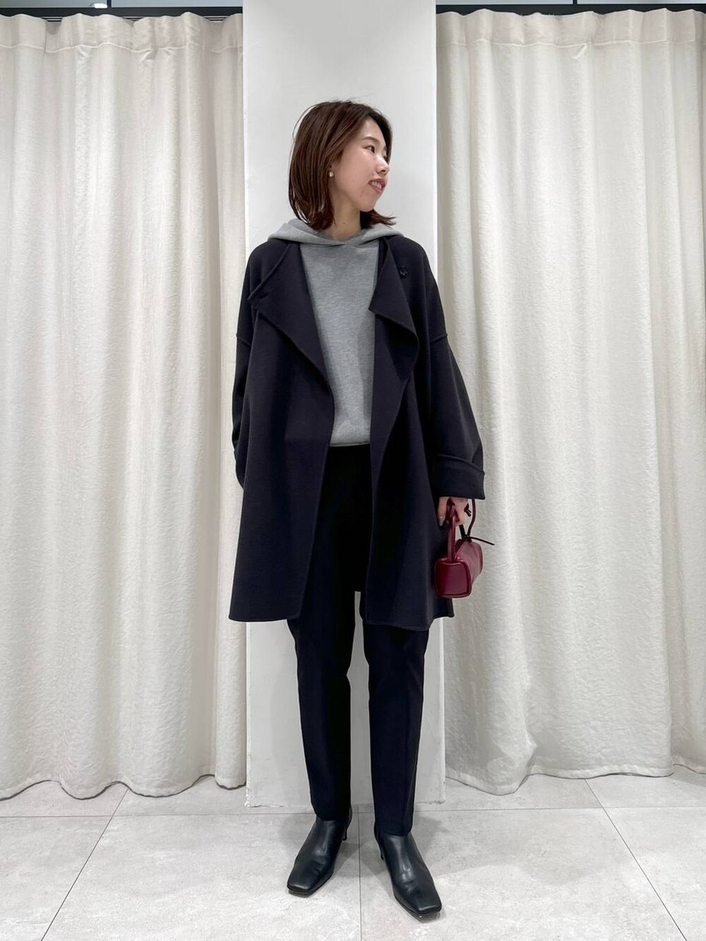 レッド系のショルダーバッグ、ブラック系のスラックス、グレー系のパーカーを着用したレディースの秋コーディネートの7枚目の写真