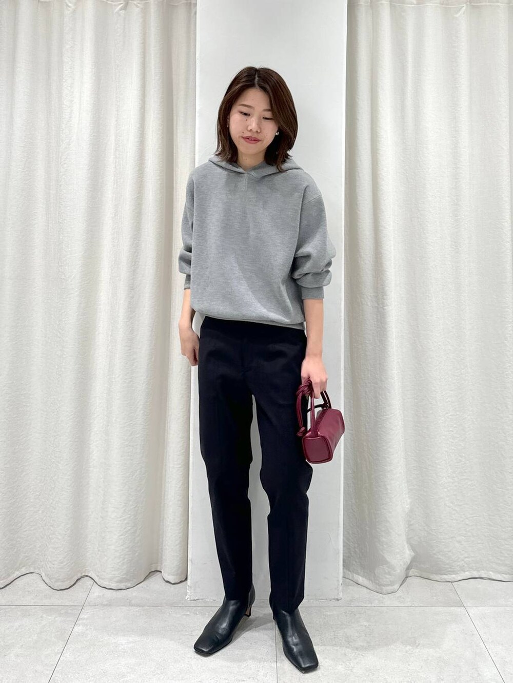 レッド系のショルダーバッグ、ブラック系のスラックス、グレー系のパーカーを着用したレディースの秋コーディネートの4枚目の写真