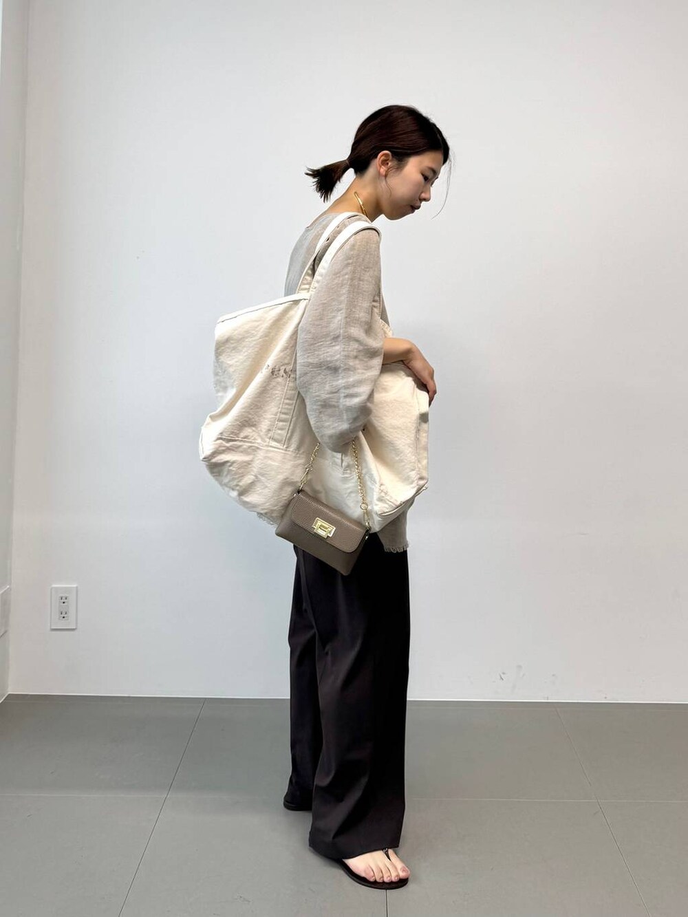 ブラウン系のサンダル、ホワイト系のトートバッグ、ベージュ系のその他トップスを着用したレディースの夏コーディネートの3枚目の写真