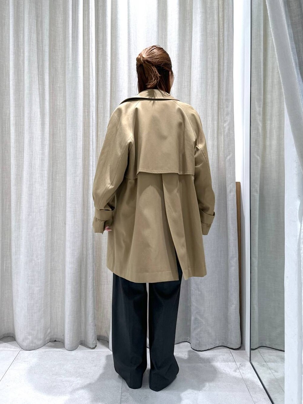 グレー系のスラックス、イエロー系のトレンチコート、イエロー系のニット/セーターを着用したレディースの秋コーディネートの6枚目の写真