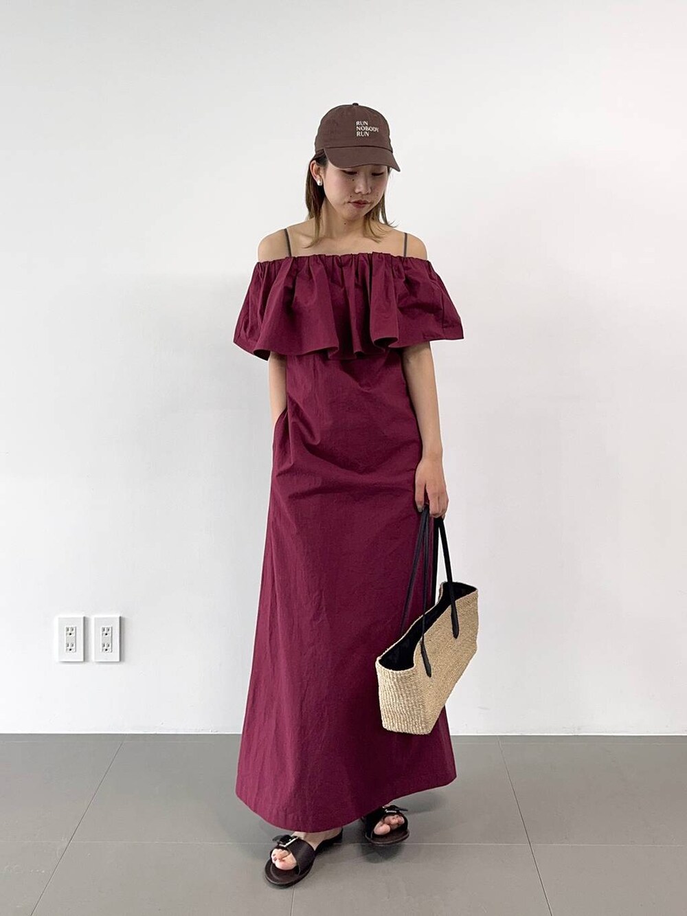 ベージュ系のかごバッグ、レッド系のワンピース、ブラウン系のキャップを着用したレディースの春コーディネートの2枚目の写真