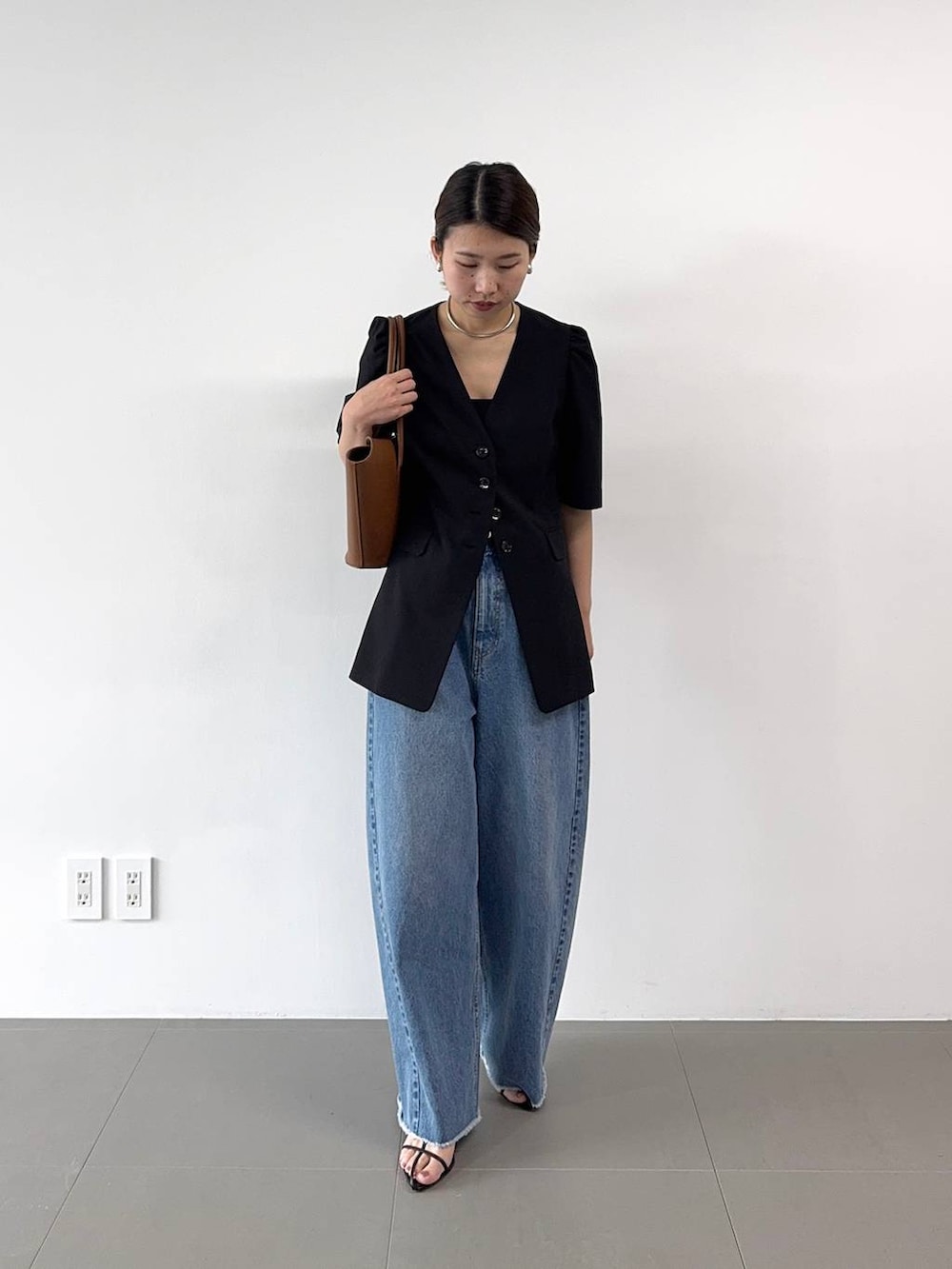 ブラック系のサンダル、ブルー系のデニムパンツ、イエロー系のハンドバッグを着用したレディースの春コーディネートの3枚目の写真