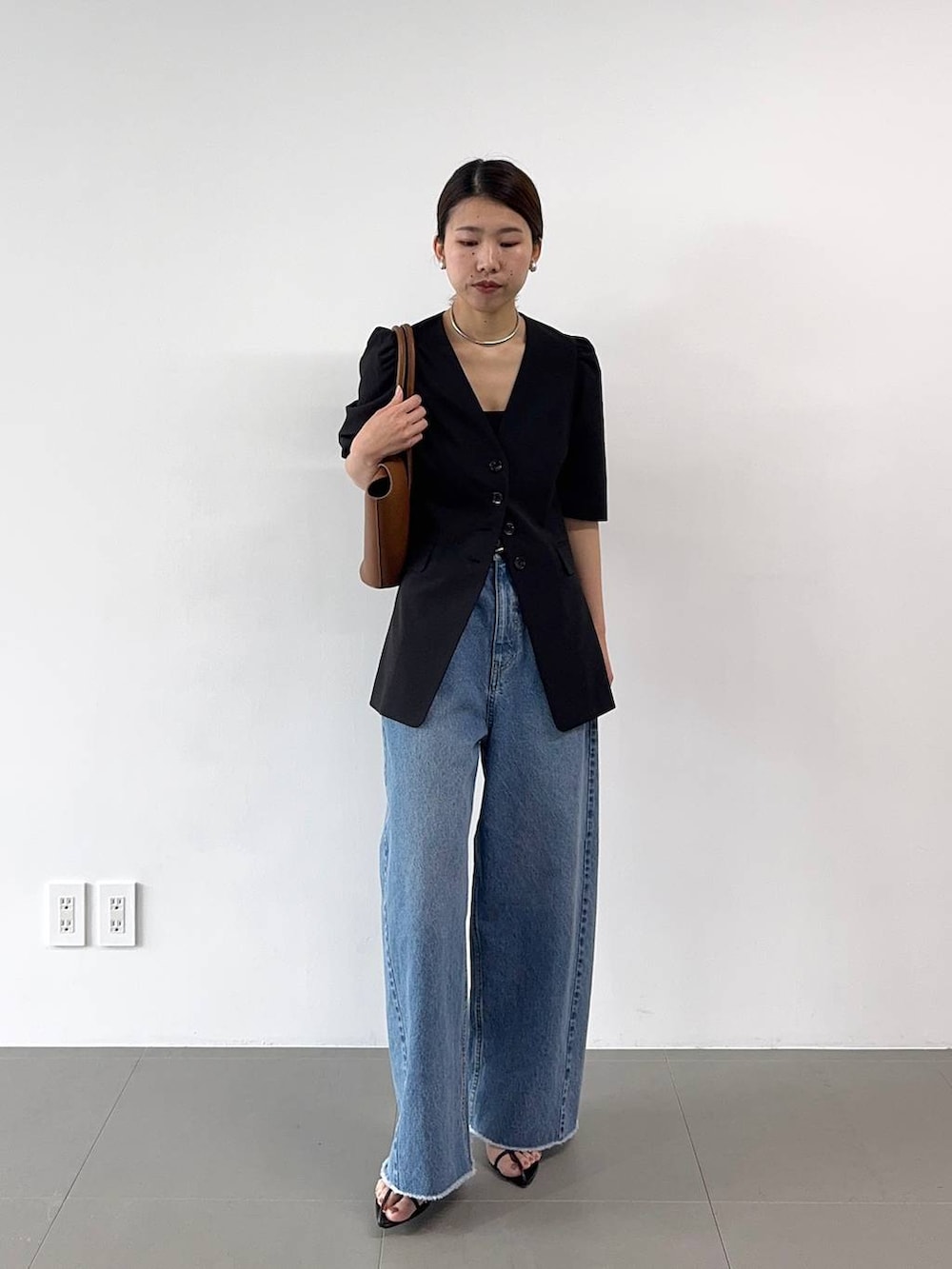 ブラック系のサンダル、ブルー系のデニムパンツ、イエロー系のハンドバッグを着用したレディースの春コーディネートの4枚目の写真