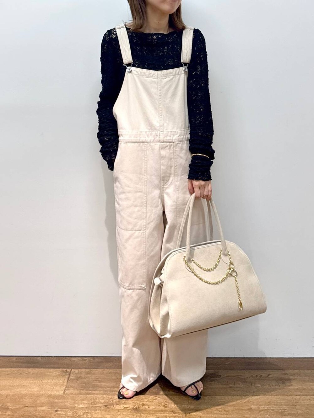 ホワイト系のサロペット/オーバーオール、ブラック系のTシャツ/カットソー、ブラック系のサンダルを着用したレディースの夏コーディネートの3枚目の写真