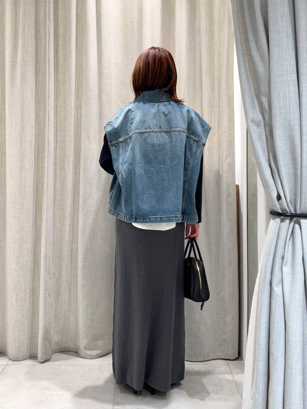 グレー系のブルゾン、ブルー系のTシャツ/カットソー、グレー系のスカートを着用したレディースの冬コーディネートの9枚目の写真