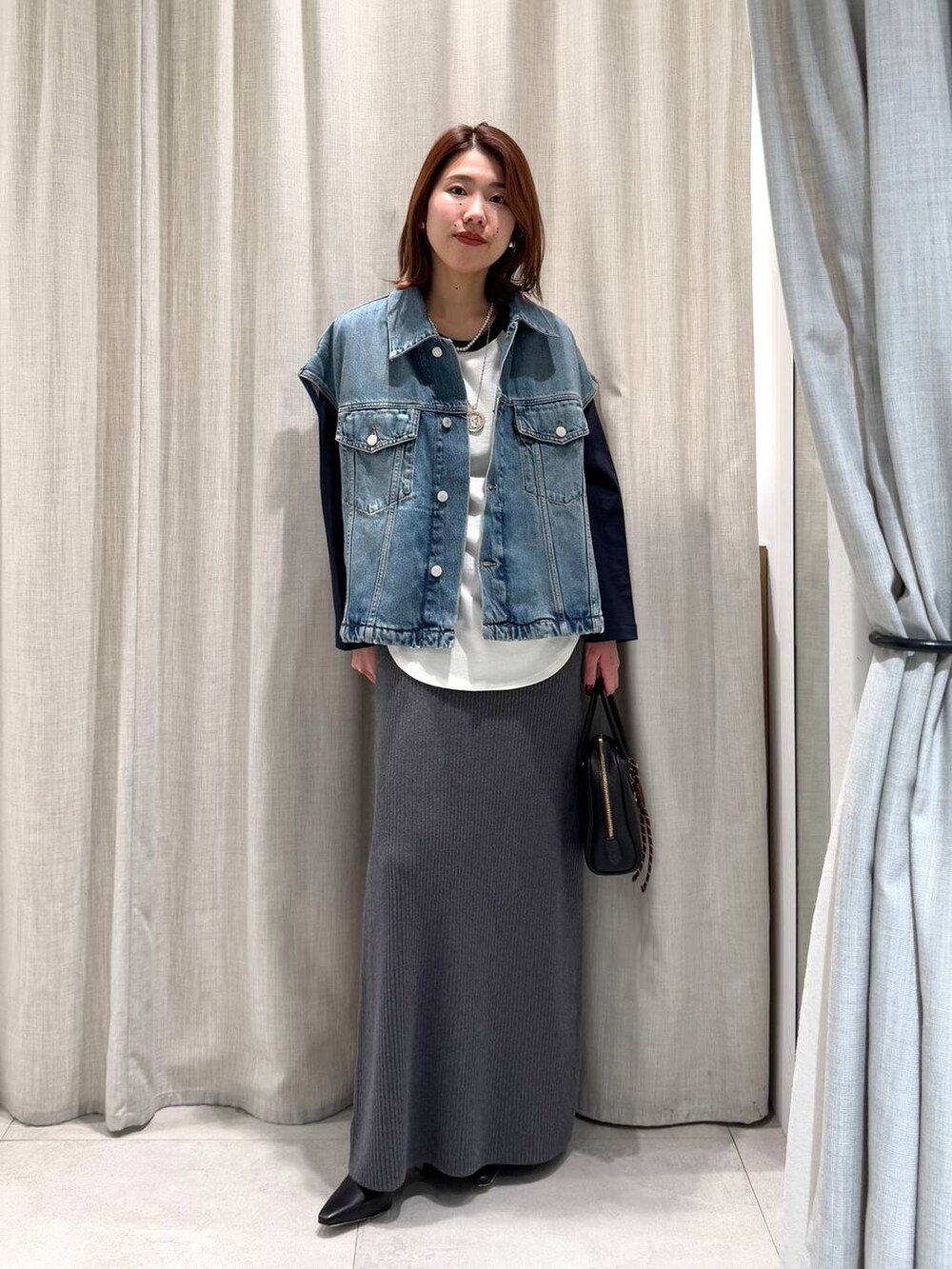 ブルー系のTシャツ/カットソー、グレー系のスカート、ブラック系のブーツを着用したレディースの冬コーディネートの4枚目の写真