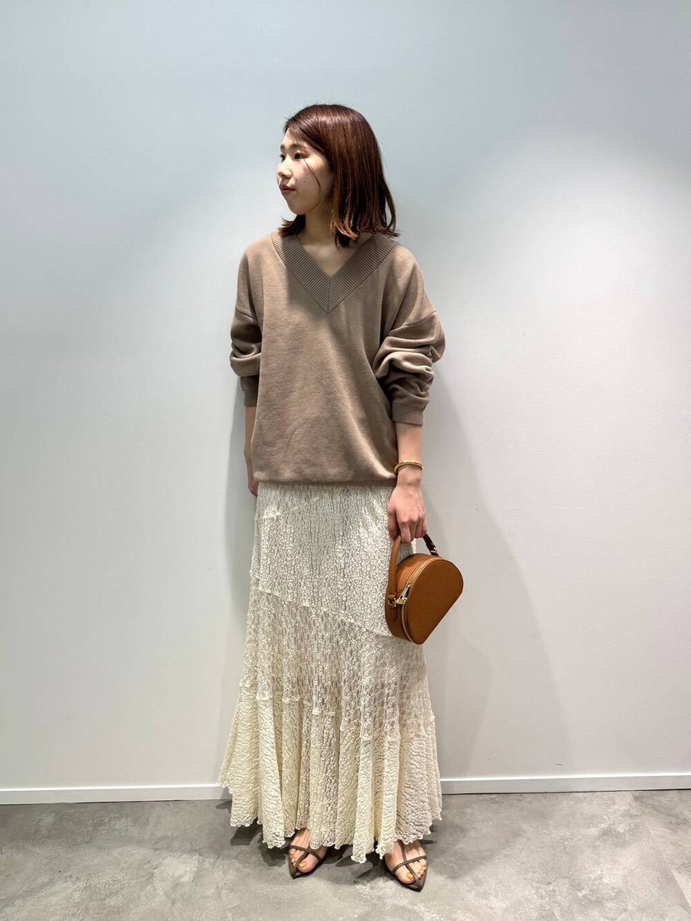 ベージュ系のサンダル、ホワイト系のスカート、イエロー系のハンドバッグを着用したレディースの夏コーディネートの2枚目の写真