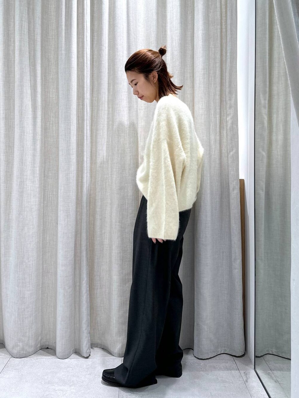 グレー系のスラックス、イエロー系のニット/セーターを着用したレディースの秋コーディネートの7枚目の写真