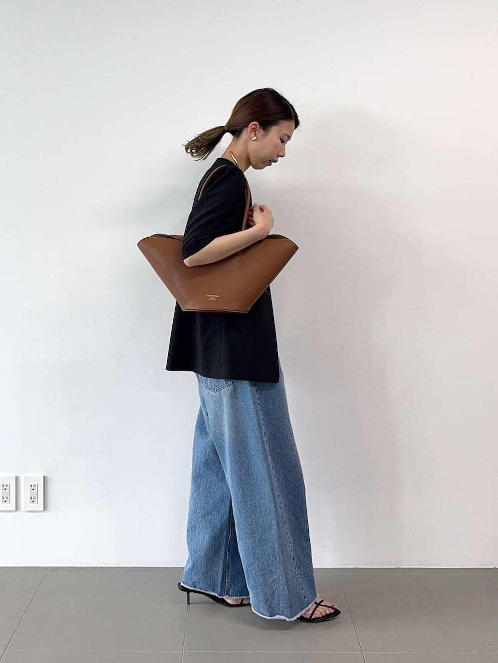 ブラック系のサンダル、ブルー系のデニムパンツ、イエロー系のハンドバッグを着用したレディースの春コーディネートの5枚目の写真