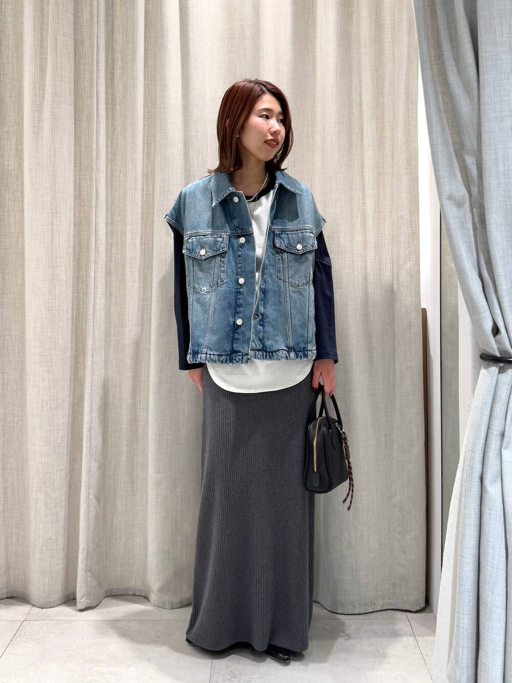 ブルー系のTシャツ/カットソー、グレー系のスカート、ブラック系のブーツを着用したレディースの冬コーディネートの2枚目の写真