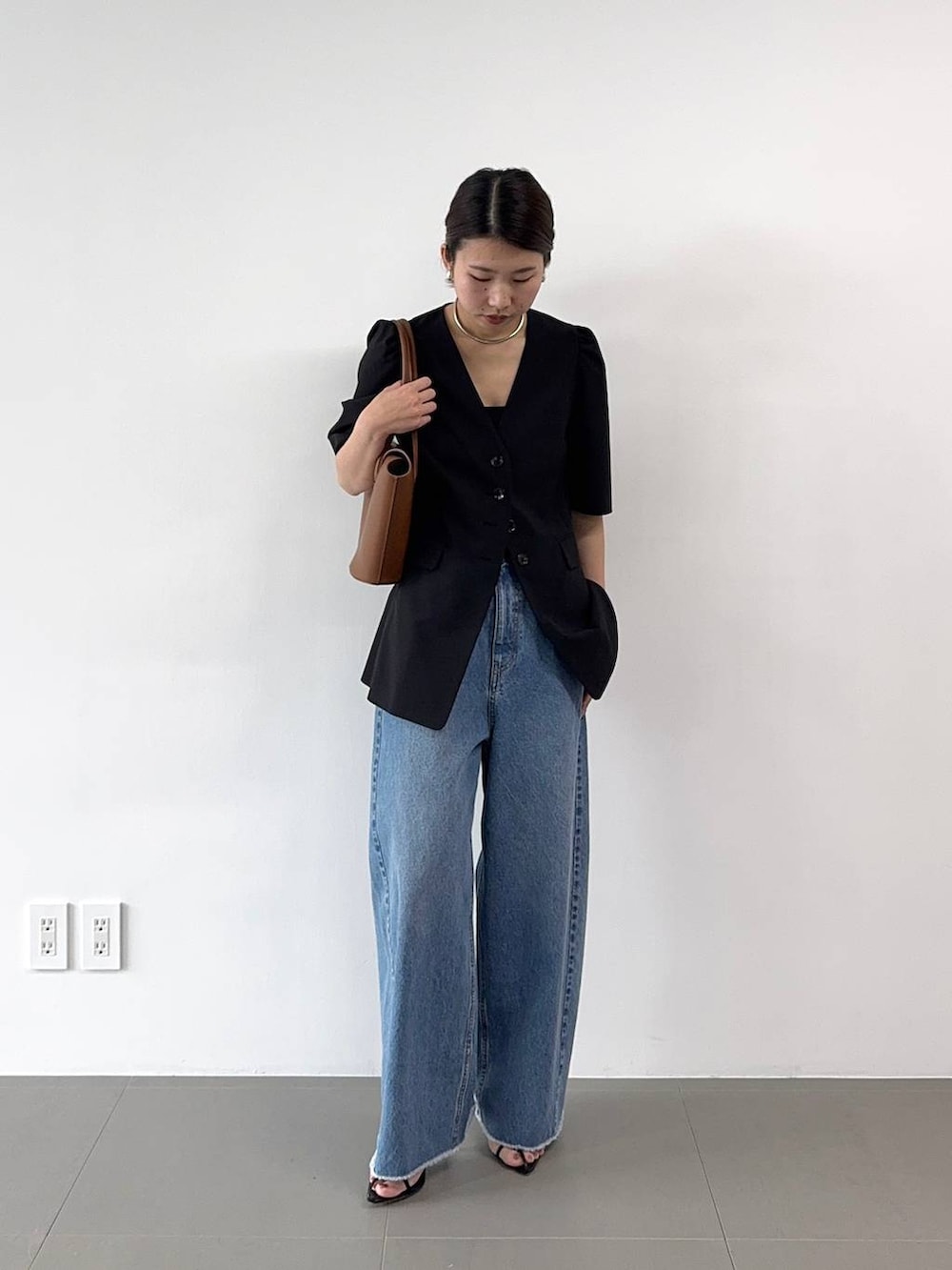 ブラック系のサンダル、ブルー系のデニムパンツ、イエロー系のハンドバッグを着用したレディースの春コーディネートの2枚目の写真