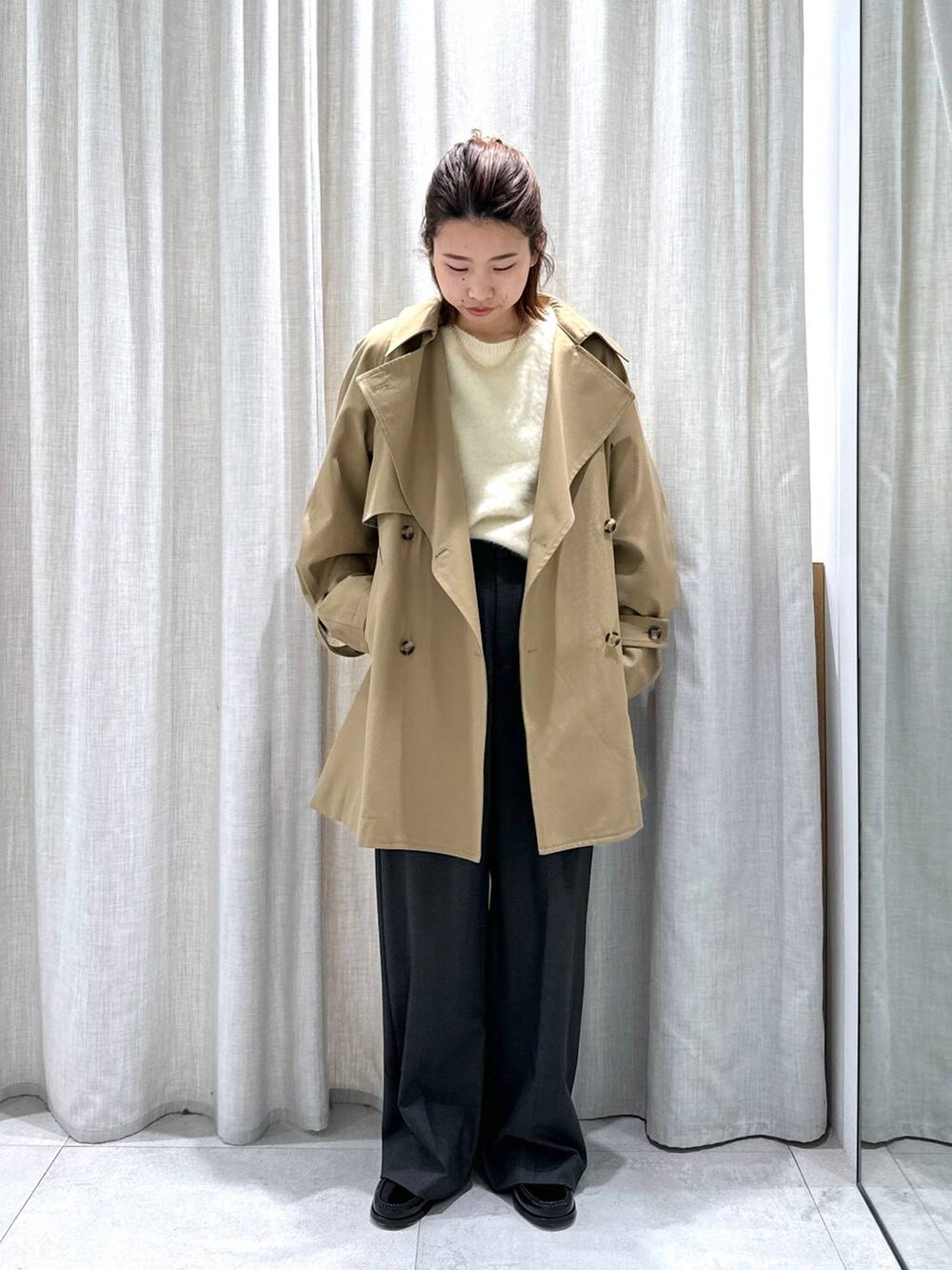 グレー系のスラックス、イエロー系のトレンチコート、イエロー系のニット/セーターを着用したレディースの秋コーディネートの2枚目の写真