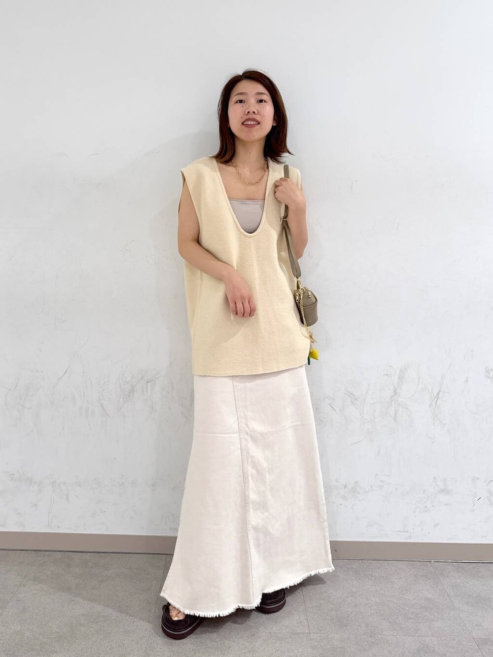 オレンジ系のキャミソール、ホワイト系のスカート、ベージュ系のベストを着用したレディースの夏コーディネートの4枚目の写真