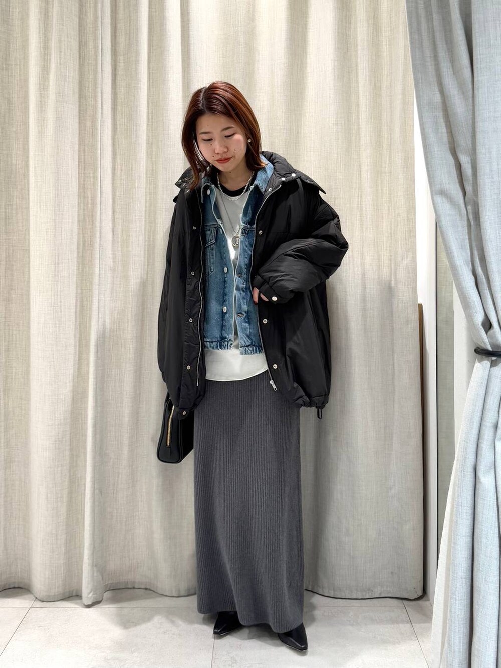 グレー系のブルゾン、ブルー系のTシャツ/カットソー、グレー系のスカートを着用したレディースの冬コーディネートの4枚目の写真