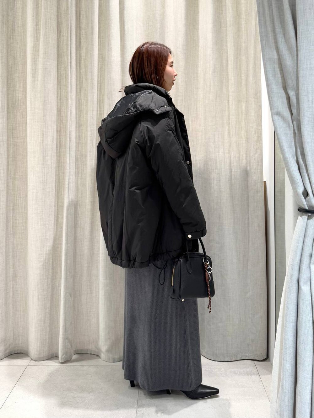 グレー系のブルゾン、ブルー系のTシャツ/カットソー、グレー系のスカートを着用したレディースの冬コーディネートの6枚目の写真