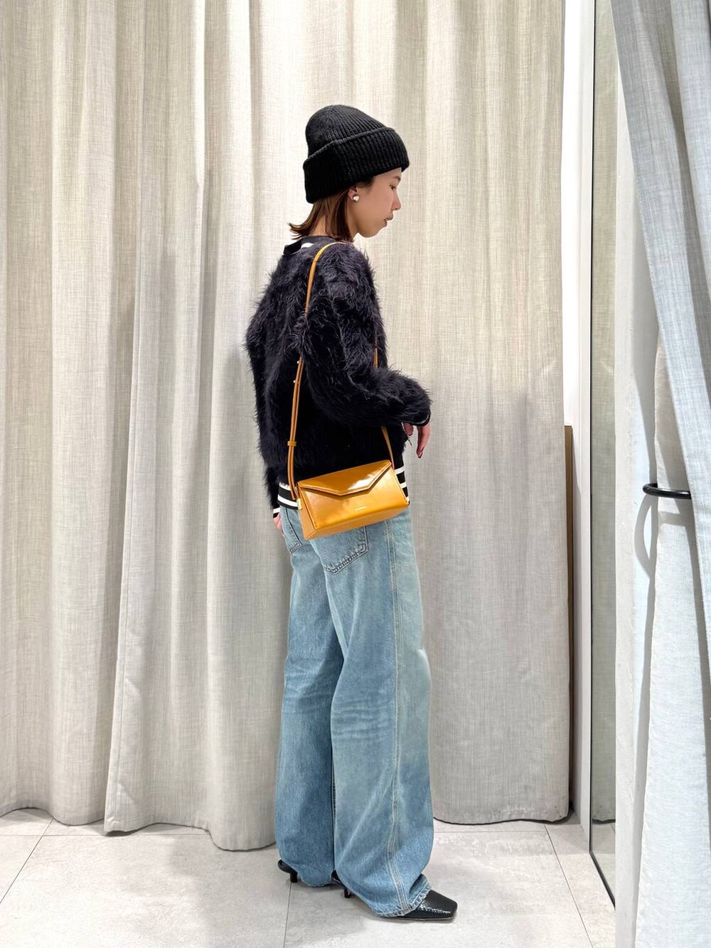 ブラック系のTシャツ/カットソー、ブルー系のカーディガン/ボレロ、ブルー系のデニムパンツを着用したレディースの冬コーディネートの5枚目の写真