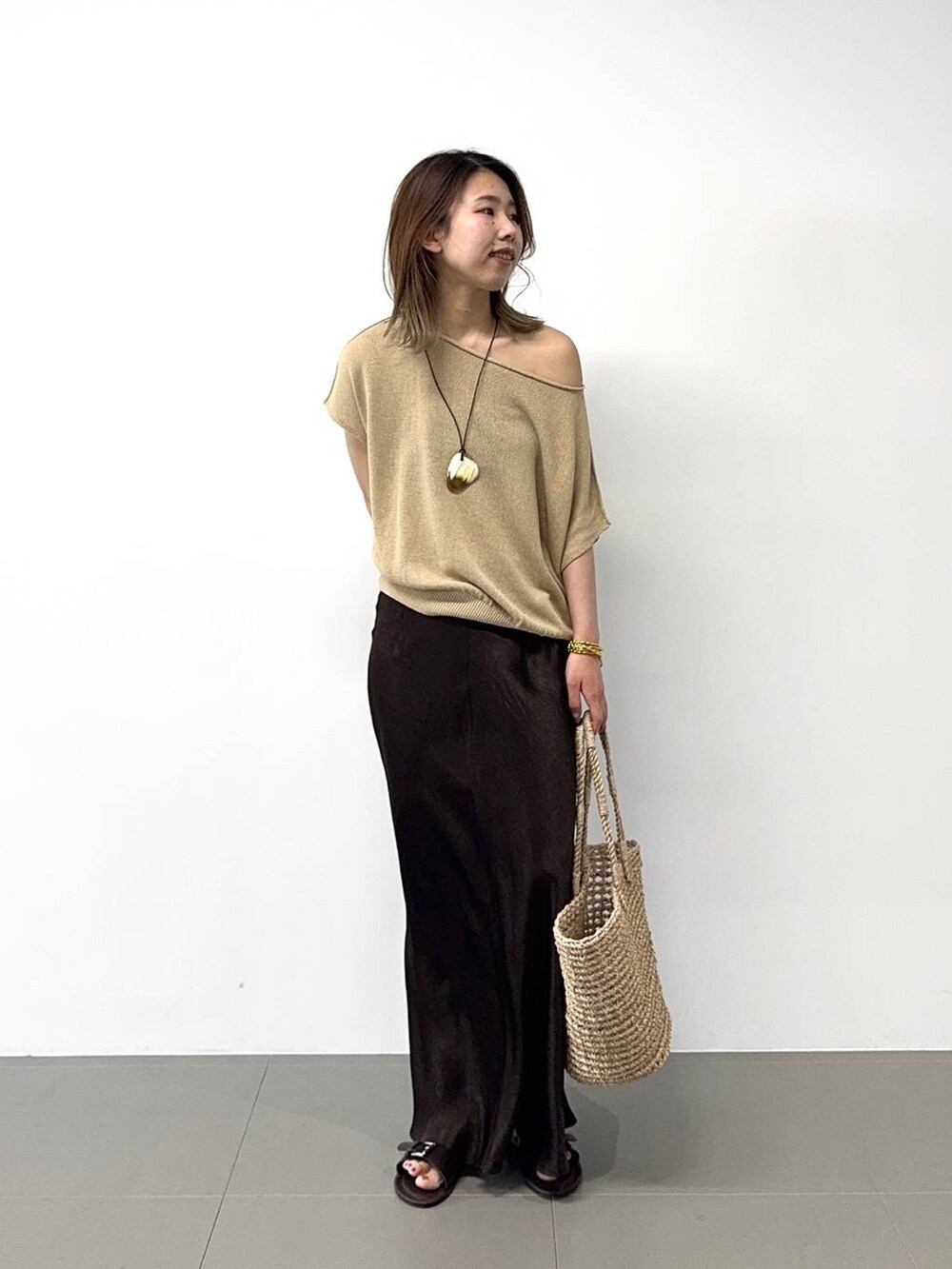 ベージュ系のかごバッグ、ベージュ系のニット/セーター、ブラウン系のスカートを着用したレディースの春コーディネートの3枚目の写真