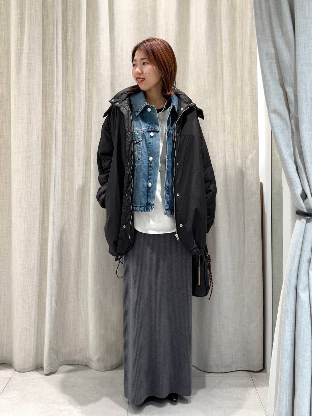 グレー系のブルゾン、ブルー系のTシャツ/カットソー、グレー系のスカートを着用したレディースの冬コーディネートの2枚目の写真