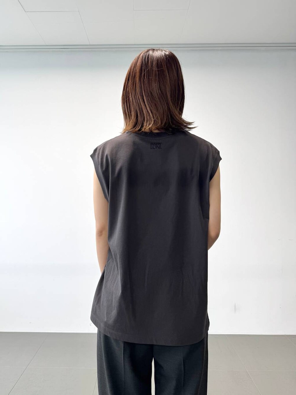 グレー系のタンクトップ、グレー系のスラックス、ブラック系のショルダーバッグを着用したレディースの夏コーディネートの9枚目の写真