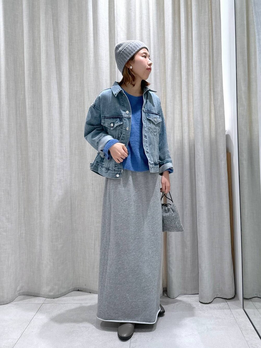 ブルー系のデニムジャケット、ブルー系のニット/セーター、シルバー系のショルダーバッグを着用したレディースの秋コーディネートの3枚目の写真