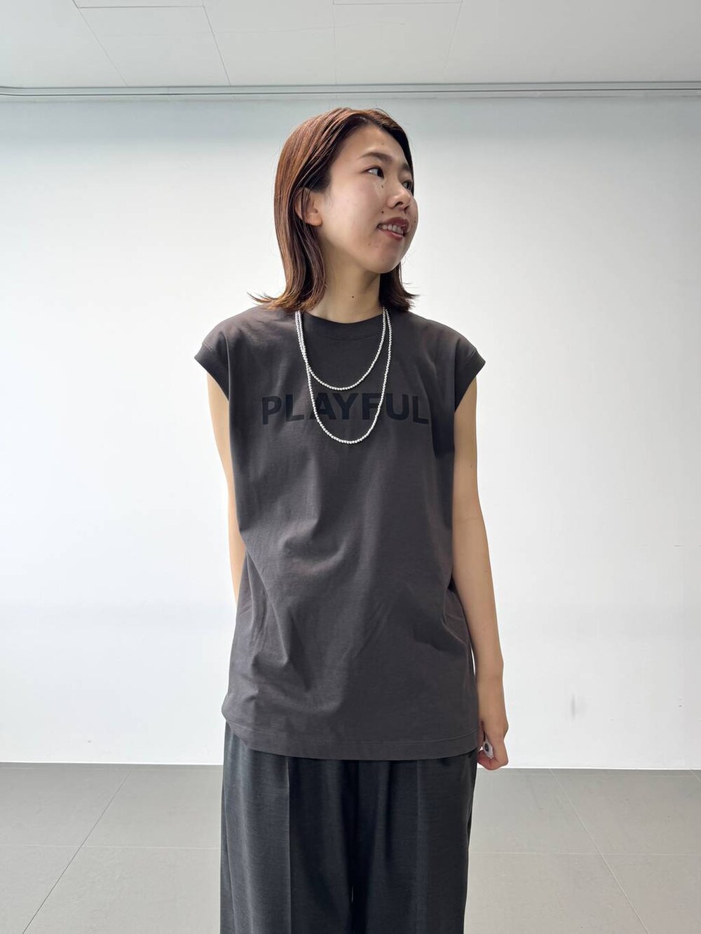 グレー系のタンクトップ、グレー系のスラックス、ブラック系のショルダーバッグを着用したレディースの夏コーディネートの8枚目の写真