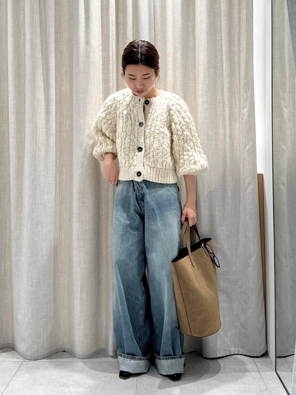 ベージュ系のカーディガン/ボレロ、ブラウン系のサンダル、ブルー系のデニムパンツを着用したレディースの秋コーディネートの2枚目の写真