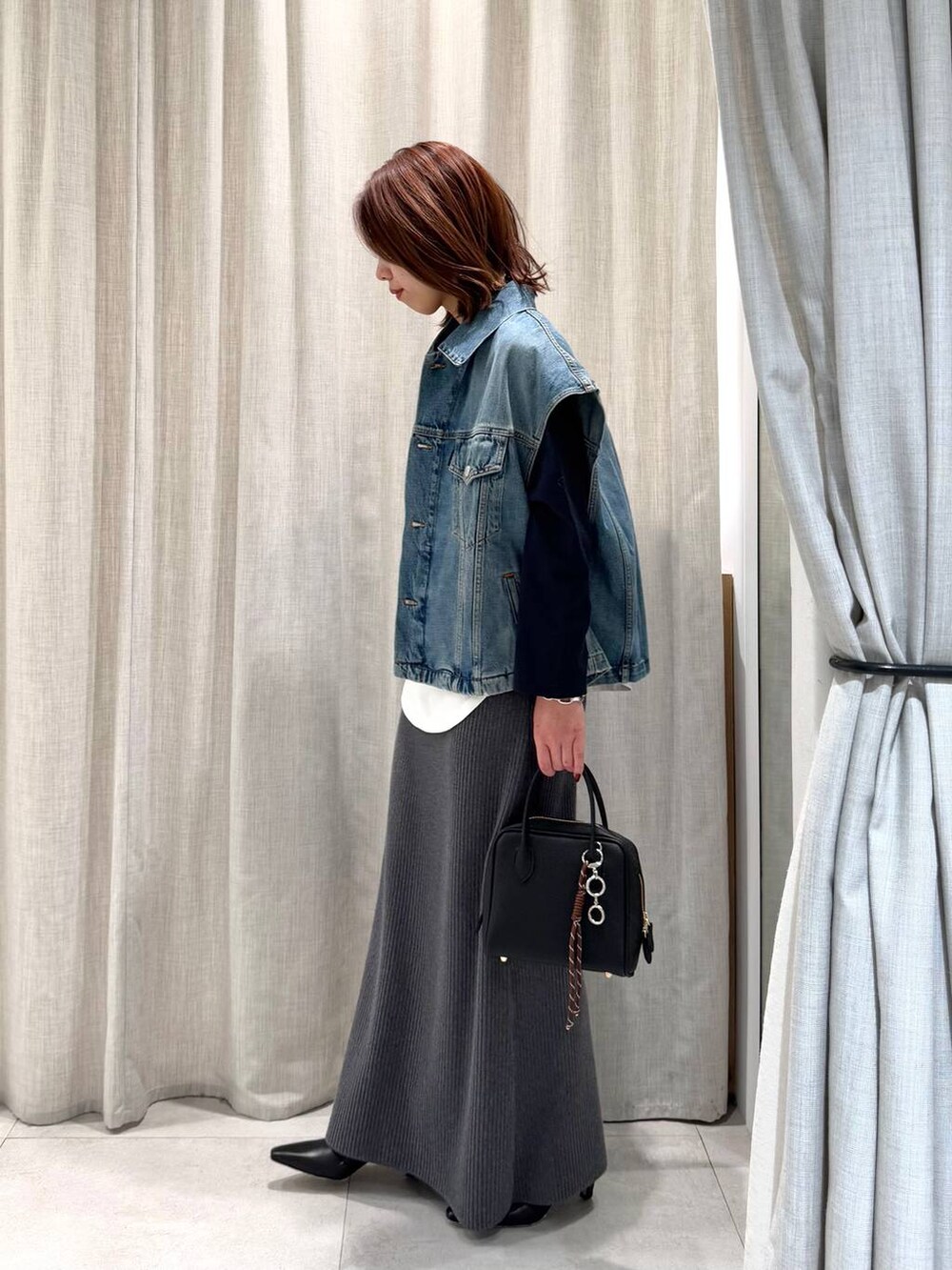 ブルー系のTシャツ/カットソー、グレー系のスカート、ブラック系のブーツを着用したレディースの冬コーディネートの5枚目の写真